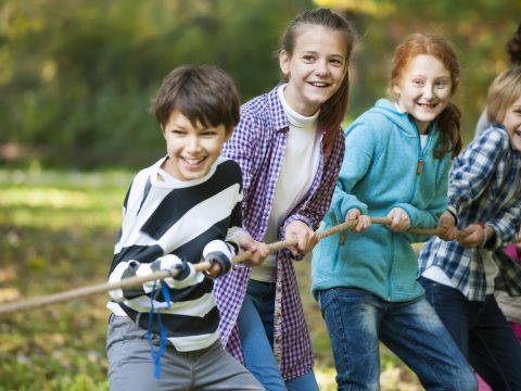 group of children playing tug of war and laughing